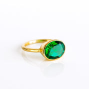 A modern oval emerald ring with bezel setting in gold vermeil, featuring a vivid green emerald-color quartz (8×12 mm) on a slim stackable band. Handmade in the USA, this May birthstone ring is available in sizes 5–10 and offered in sterling silver and rose gold vermeil as well. A dainty yet eye-catching green gemstone ring—perfect for birthdays, anniversaries, or everyday minimalist style.
