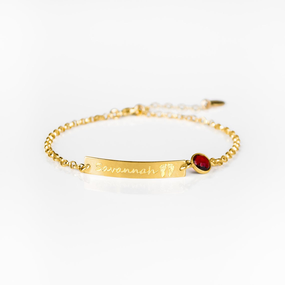 Single gold filled footprint and name engraved bar bracelet with garnet birthstone on white background. New mom gift, push present, birthday, mother's day.