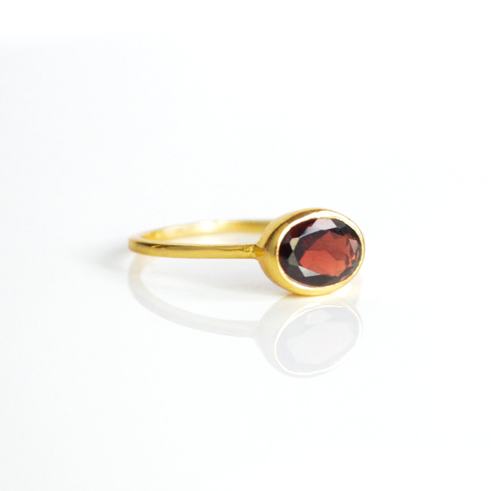 a gold garnet ring shown on white background. stackable! Stacking rings, bezel set, small oval, tiny oval, dainty oval, birthstone rings, sterling silver stamp, birthstone ring, birthstone jewelry, red gemstone, red birthstone, january birthstone, january gemstone