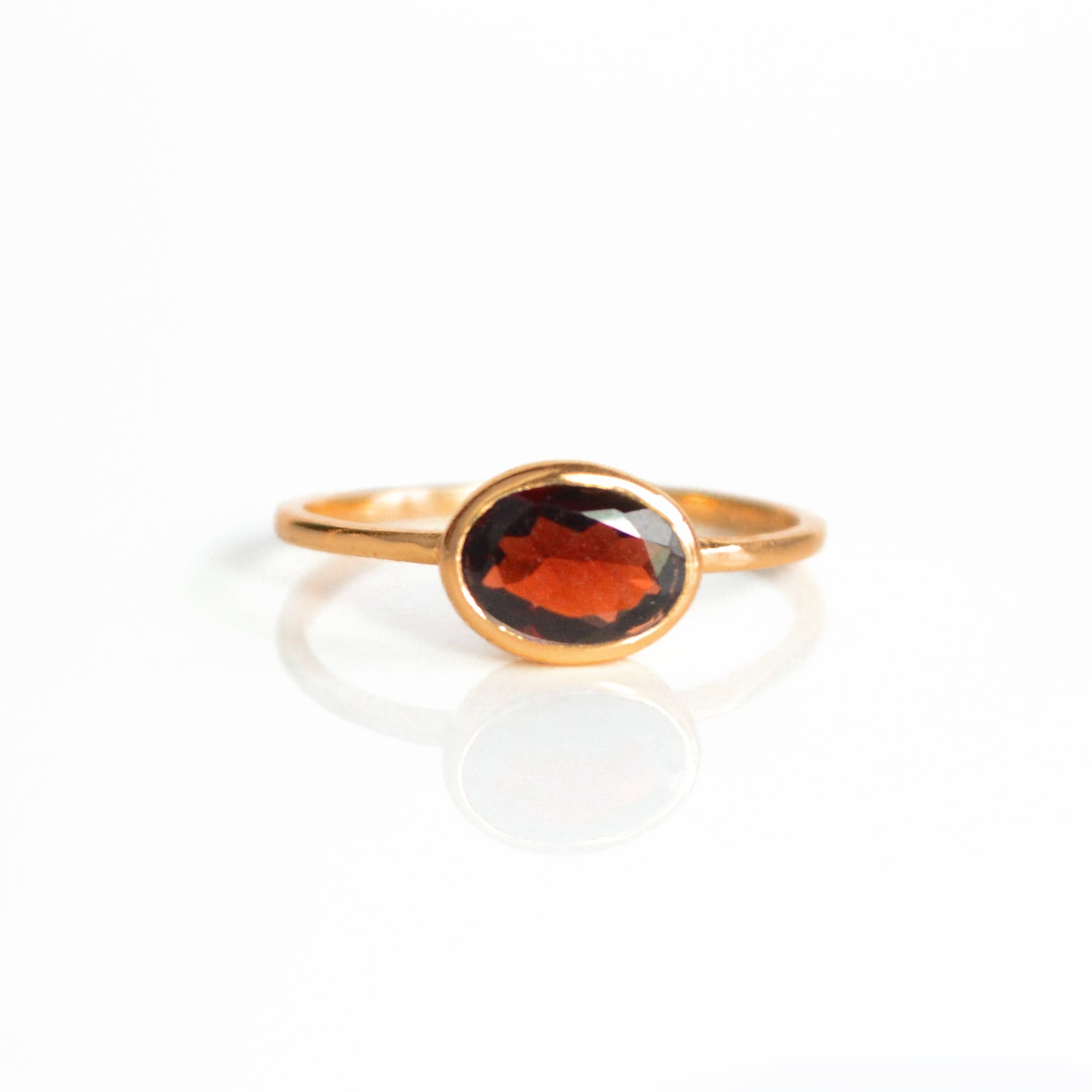 a rose gold garnet ring shown on white background. stackable! Stacking rings, bezel set, small oval, tiny oval, dainty oval, birthstone rings, sterling silver stamp, birthstone ring, birthstone jewelry, red gemstone, red birthstone, january birthstone, january gemstone