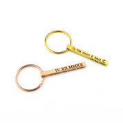 Pair of slim bar keychains in gold and rose gold finishes displayed on a clean white backdrop, each etched with short phrases to show character limits on the dainty bar. Matching spring rings keep the minimalist profile sleek. Great custom bar keychain option for couples, bridesmaids or groomsmen keychain gifts, new-driver reminders, and short motivational quotes.