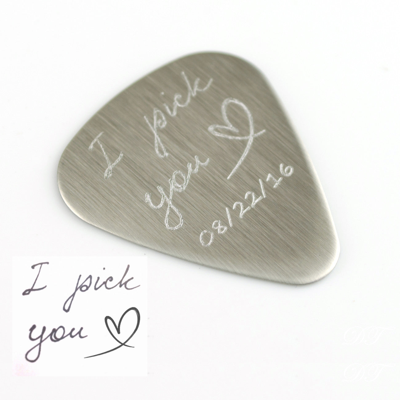 Single guitar pick with I pick you design, heart and date engraved on white background.