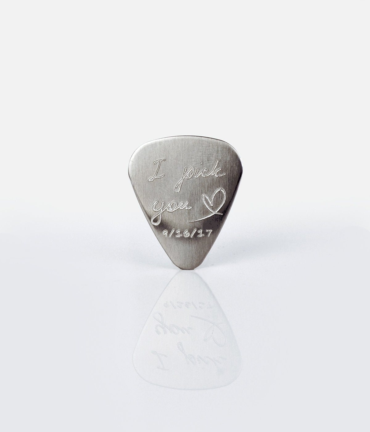 Single guitar pick with I pick you design, heart and date engraved on white background.