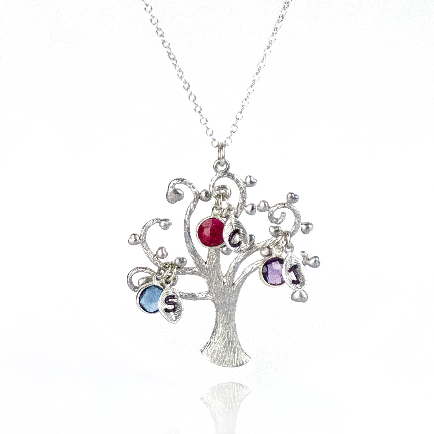 Single silver swirly tree necklace with hand stamped leaf charms and kyanite, dyed ruby and purple amethyst birthstones. 