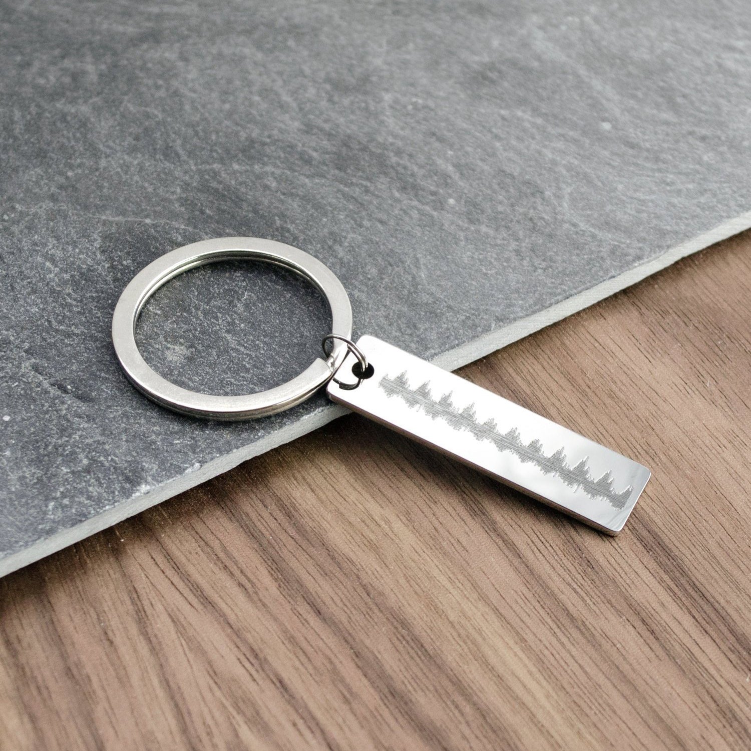 Single silver skinny rectangle keychain with a heartbeat engraved on one side. 