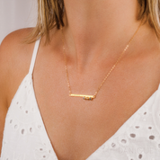 Model in white top is wearing Gold plated skinny bar necklace with initials engraved with the purple amethyst, citrine and iolite birthstones. 