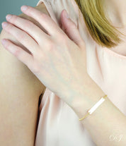 Model in cream top is wearing the engraved gold filled bar bracelet.