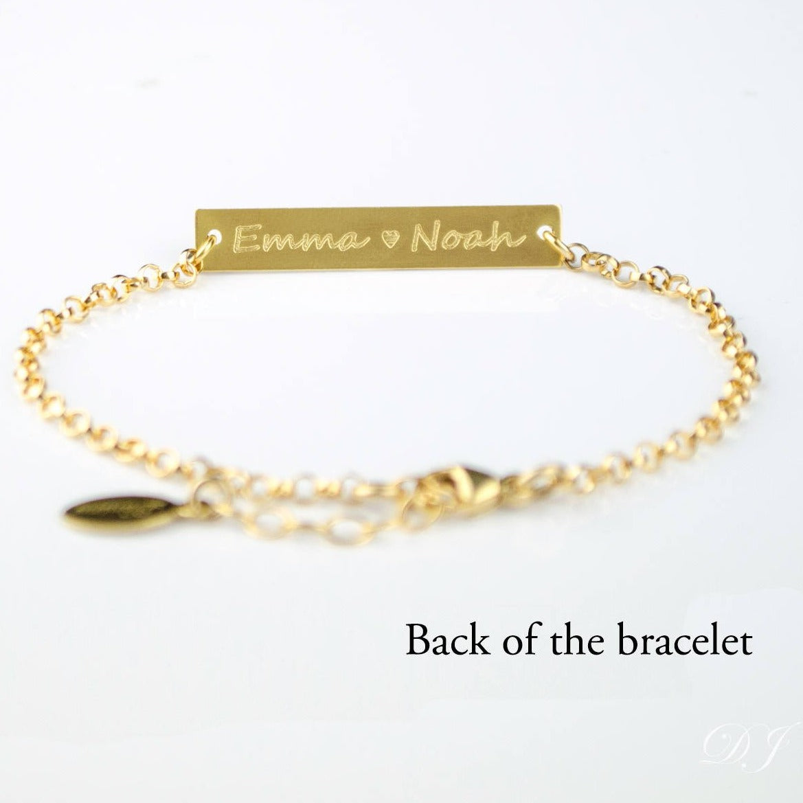 Back of the gold filled bar bracelet is displayed with two names and a heart emjoi engraved in our script font. 