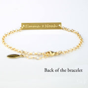 Back of the gold filled bar bracelet is displayed with two names and a heart emjoi engraved in our script font. 