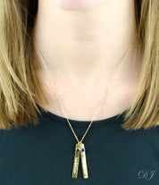 Model in black top is wearing the gemstone bar necklace in Gold filled satellite necklace with two bars and gemstones with engraved names in script font. One kyanite birthstone and one purple amethyst birthstone