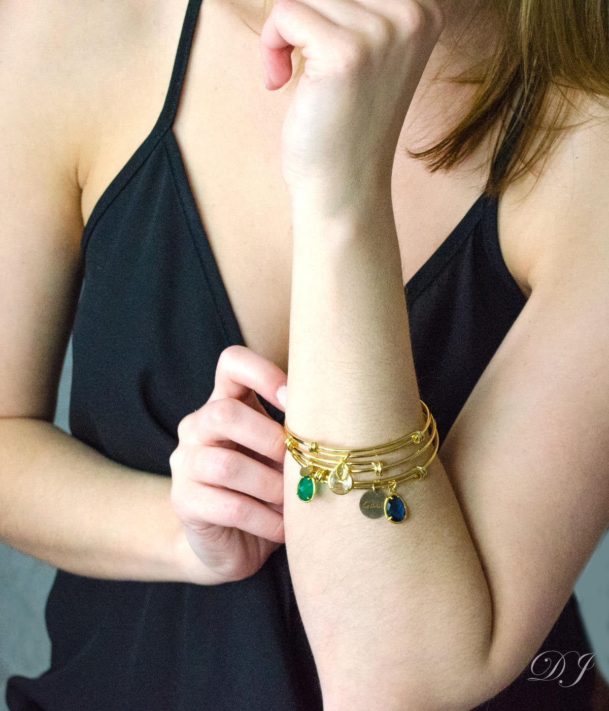 Model in black top is stylishly layering three gold bangles with citrine, green onyx and kyanite birthstones