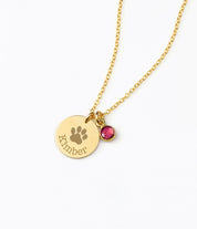 A gold engraved paw print necklace with a ruby July birthstone.  Paw print disc necklace, dainty pet jewelry, custom birthstone necklace, sterling silver pet necklace, gold-filled disc pendant, rose gold-filled pet necklace, personalized pet lover gift, custom engraved jewelry, pet keepsake necklace, unique pet memorial necklace