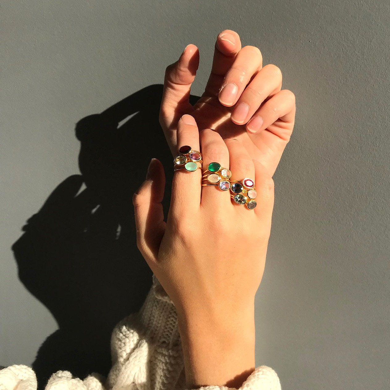 Model showcasing our stackable tiny oval rings. four on index finger, 4 on middle finger, 5 on ring finger. 