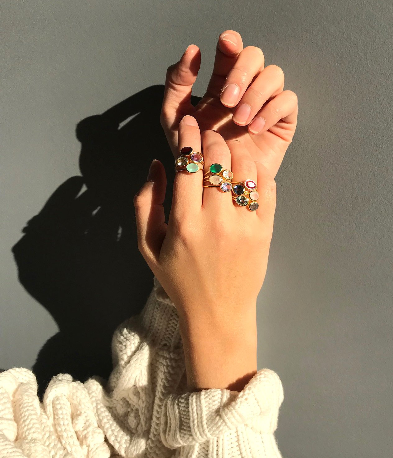 Model showcasing our stackable tiny oval rings. four on index finger, 4 on middle finger, 5 on ring finger. 