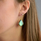 Gold labradorite earrings pear shaped gemstone drop earrings on a model