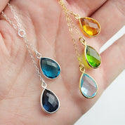 Assortment of glossy teardrop gemstones in bezel settings demonstrating available birthstone options for the lariat design—rich blues, golden yellows, greens, and clear stones. Highlights premium 18k vermeil or sterling bezels and the handcrafted quality. Great for customizing a peace-themed or charity necklace. Keywords: teardrop birthstone, birthstone drop necklace, customizable pendant, fundraiser jewelry, gold filled necklace.