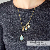 Model wearing a 20" gold filled branch necklace with aqua chalcedony as the large stone and three birthstones in clear, sky blue and moonstone with name tags