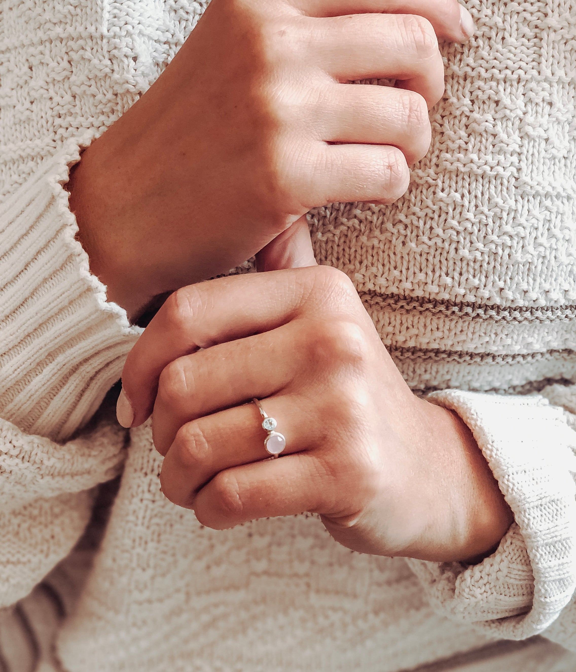 Model is wearing the mothers duel bezel set ring in sterling silver featuring a 5mm pink chalcedony and 3mm blue topaz birthstones.
