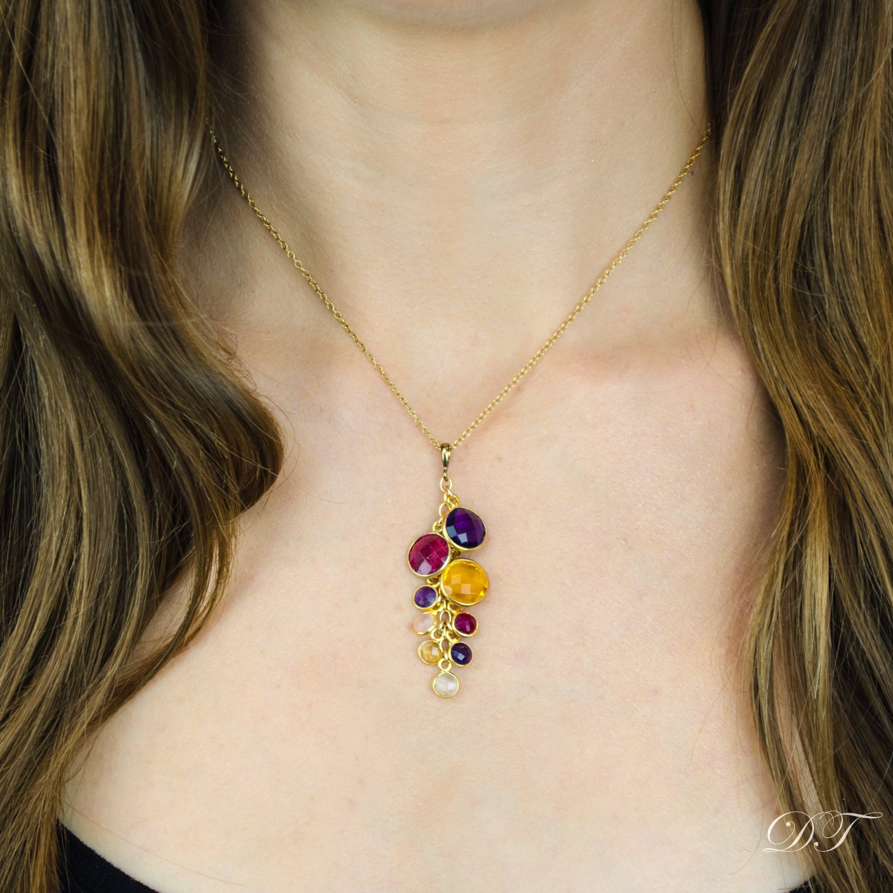 Model is wearing a gold cable necklace with lapis, garnet, citrine, kyanite, garnet, clear, citrine, kyanite and moonstone birthstones. 