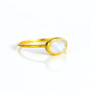 a gold rainbow moonstone ring shown on white background. stackable! Stacking rings, bezel set, small oval, tiny oval, dainty oval, birthstone rings, sterling silver stamp, birthstone ring, birthstone jewelry, white iridescent gemstone, moonstone birthstone, june birthstone, june gemstone, stack set, stacking rings, gemstone ring, birthstone ring, mother's day gift for her, gift for mom, gift for fiance, gift for girlfriend, wedding jewelry, bridesmaid jewelry, anniversary jewelry, anniversary gift, birthday