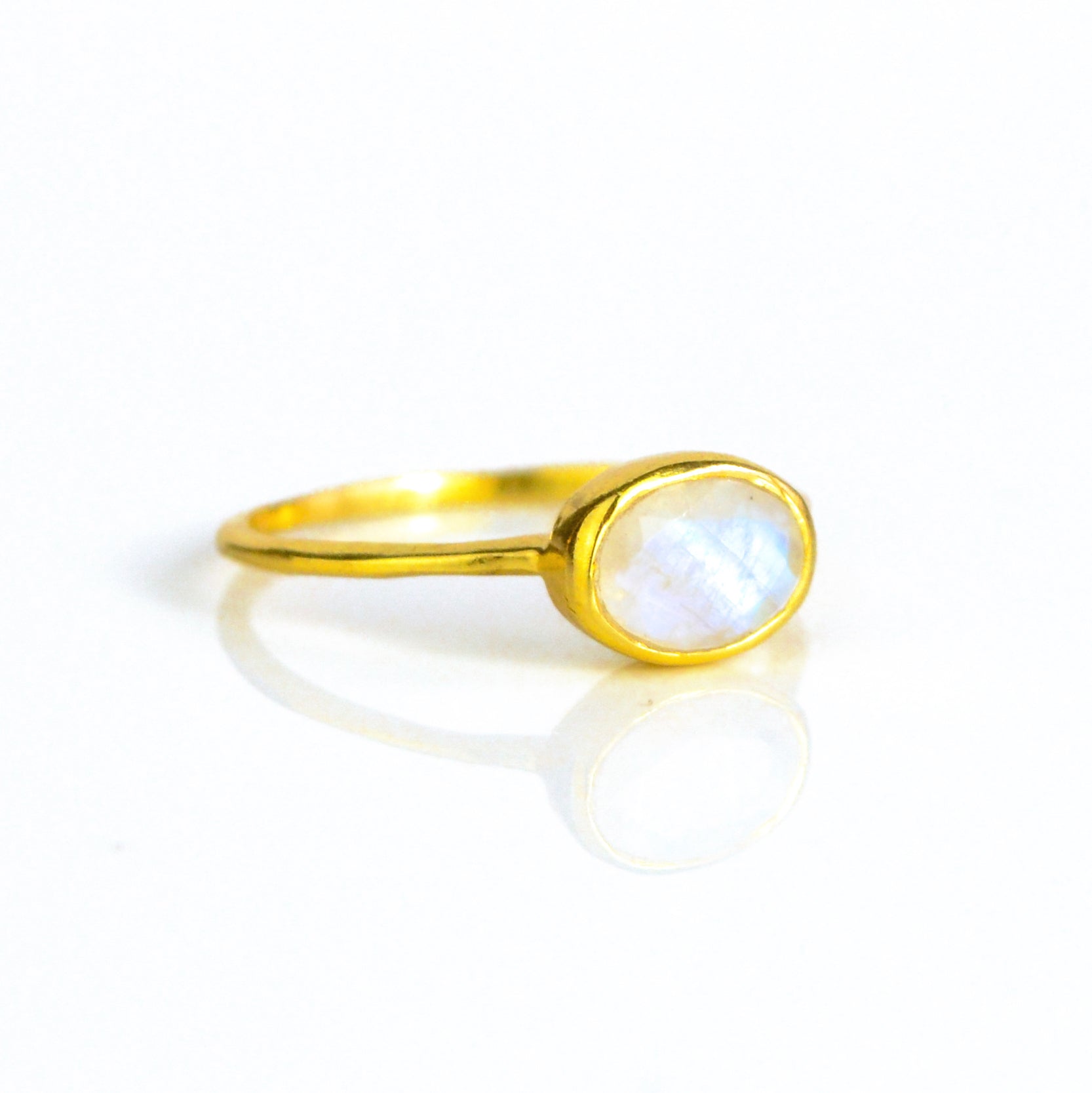 a gold rainbow moonstone ring shown on white background. stackable! Stacking rings, bezel set, small oval, tiny oval, dainty oval, birthstone rings, sterling silver stamp, birthstone ring, birthstone jewelry, white iridescent gemstone, moonstone birthstone, june birthstone, june gemstone, stack set, stacking rings, gemstone ring, birthstone ring, mother's day gift for her, gift for mom, gift for fiance, gift for girlfriend, wedding jewelry, bridesmaid jewelry, anniversary jewelry, anniversary gift, birthday