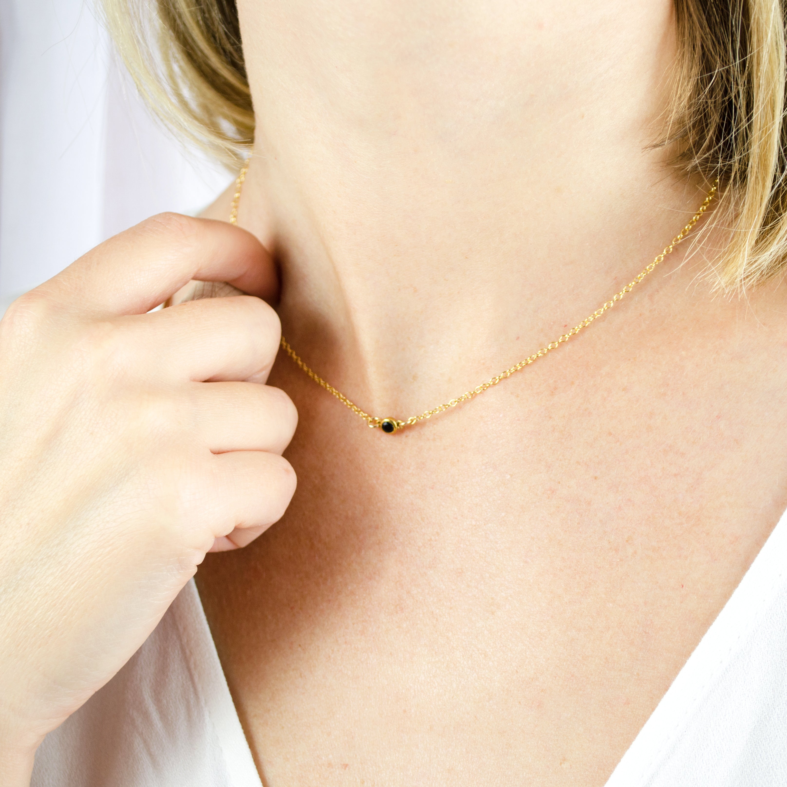 Model in white top is wearing a gold filled dainty 3mm connector necklace with black onyx birthstone. 