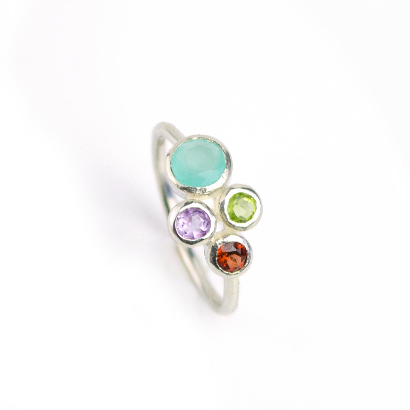 Single sterling silver ring with aqua chalcedony, purple amethyst, garnet and peridot birthstones on a white background.