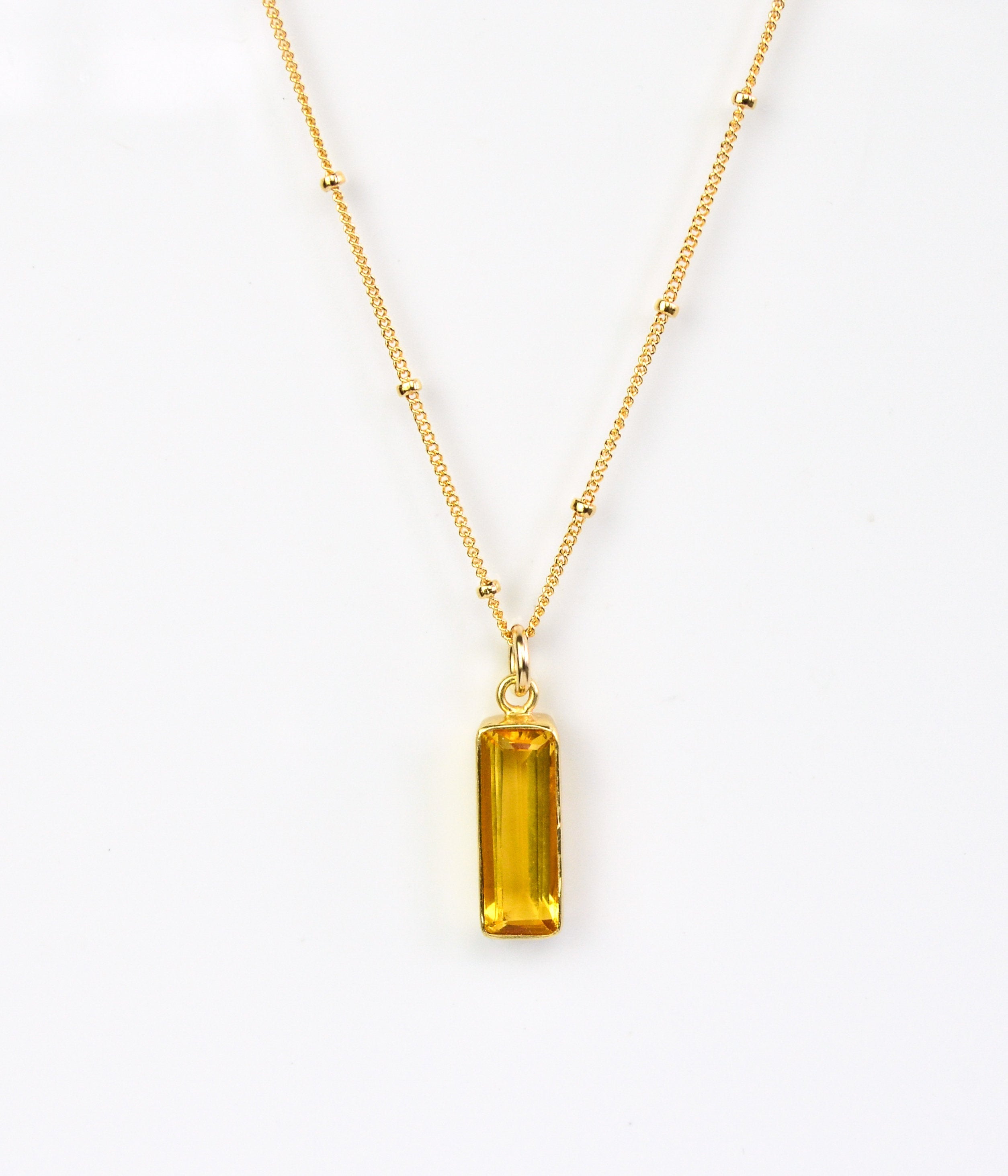 Single gold filled satellite chain vertical citrine november birthstone adira bar necklace on white background.