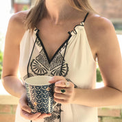 Lifestyle image of a woman wearing a rainbow moonstone oval ring while holding a drink, showcasing the ring styled for everyday fashion. Bezel-set June birthstone ring with a luminous oval moonstone, designed in a minimalist, modern style. Elegant gemstone jewelry perfect for daily wear, layering, and thoughtful gifting for her.