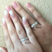 Two hands on top of each other, each wearing an engraved fingerprint ring. Engraved fingerprint jewelry, custom handwriting band, 4mm sterling silver ring, gold thin band, rose gold personalized ring, special names and dates, coordinates, photo engraving, stylish accessory, gift for loved ones, elegant keepsake, ring sizes 4, 5, 6, 7, 8, 9, 10, 11, 12, 13