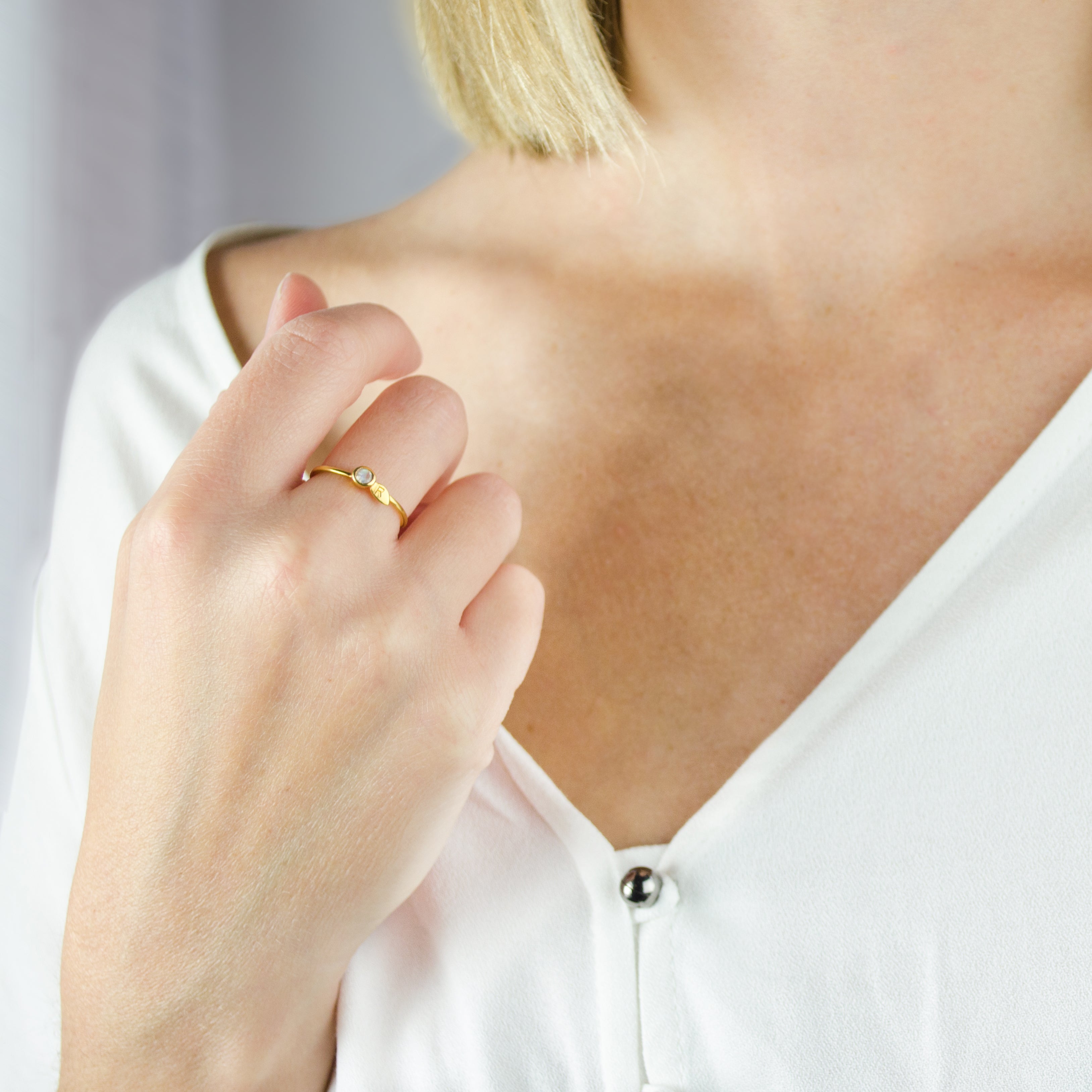 Model is wearing one gold leaf birthstone ring with custom initial engraving. 