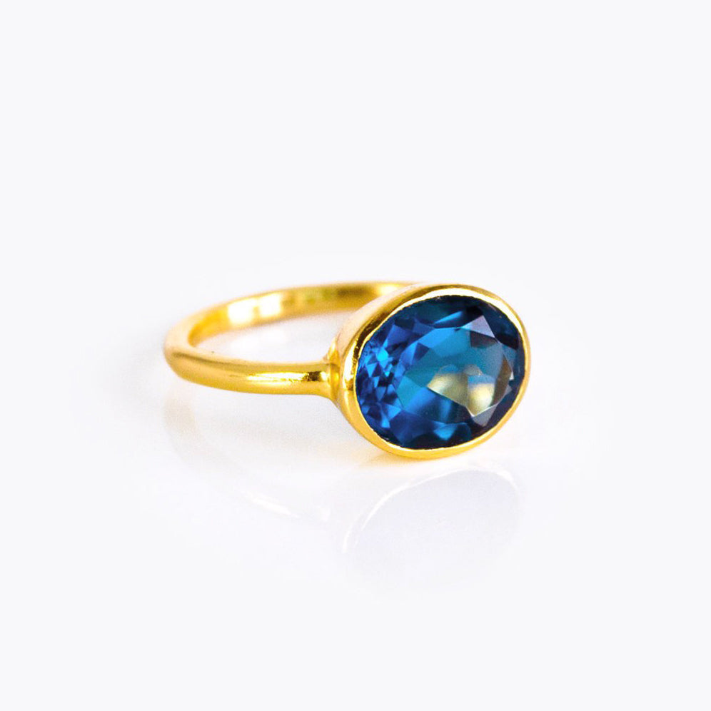 Elegant oval kyanite ring with a sapphire-blue cabochon-style faceted stone in a slim 18k gold vermeil bezel setting; minimalist September birthstone ring designed for everyday wear, stacking, promise or anniversary gifting; handmade by Danique Jewelry; available in multiple US sizes; gift-ready packaging included.