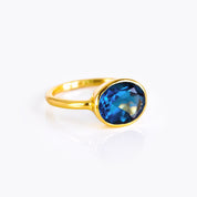Elegant oval kyanite ring with a sapphire-blue cabochon-style faceted stone in a slim 18k gold vermeil bezel setting; minimalist September birthstone ring designed for everyday wear, stacking, promise or anniversary gifting; handmade by Danique Jewelry; available in multiple US sizes; gift-ready packaging included.
