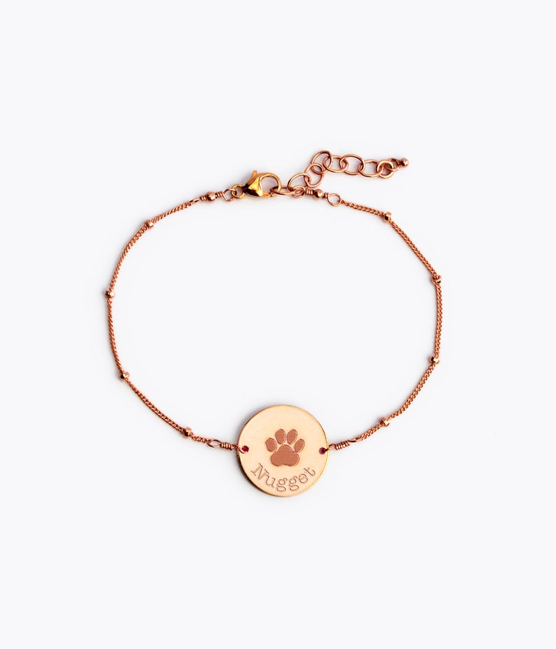 Single rose gold satellite chain with lobster clasp and paw print disc with pet name in typewriter font. 