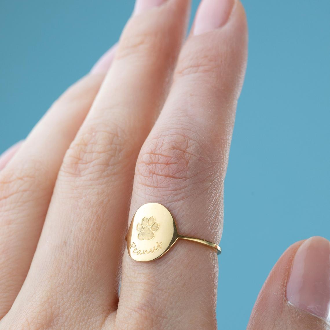 Model wearing custom paw print memorial celebration ring. Use one of our font styles to engrave a name or date. 