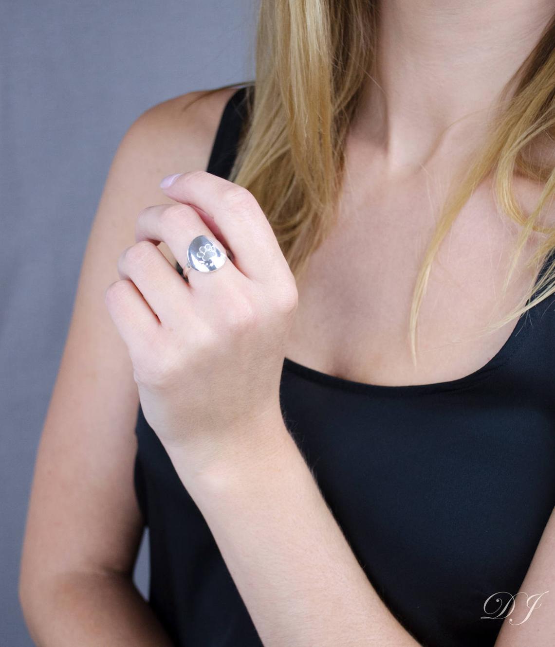Model wearing custom engraved sterling silver paw print ring.