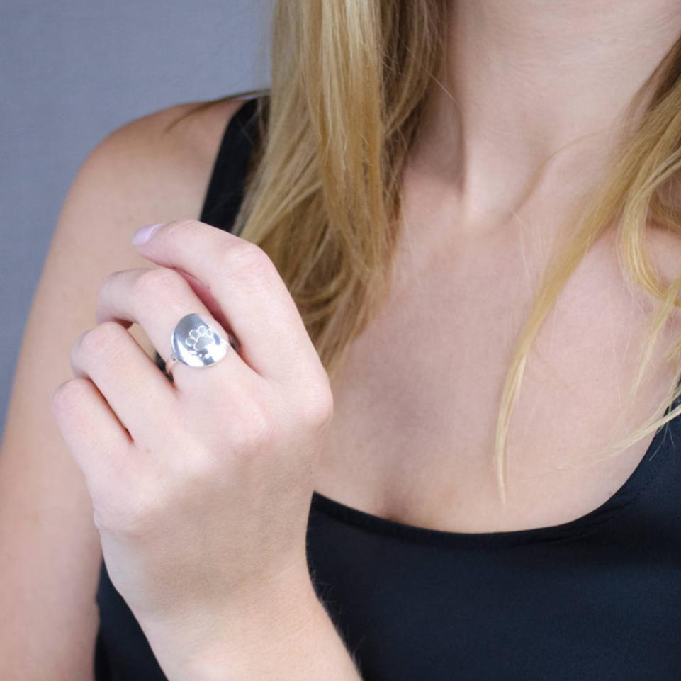 Model wearing custom engraved sterling silver paw print ring.