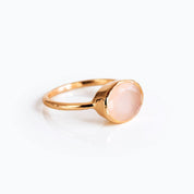 Side view of oval pink chalcedony ring in gold bezel setting, delicate blush gemstone stacking ring for women