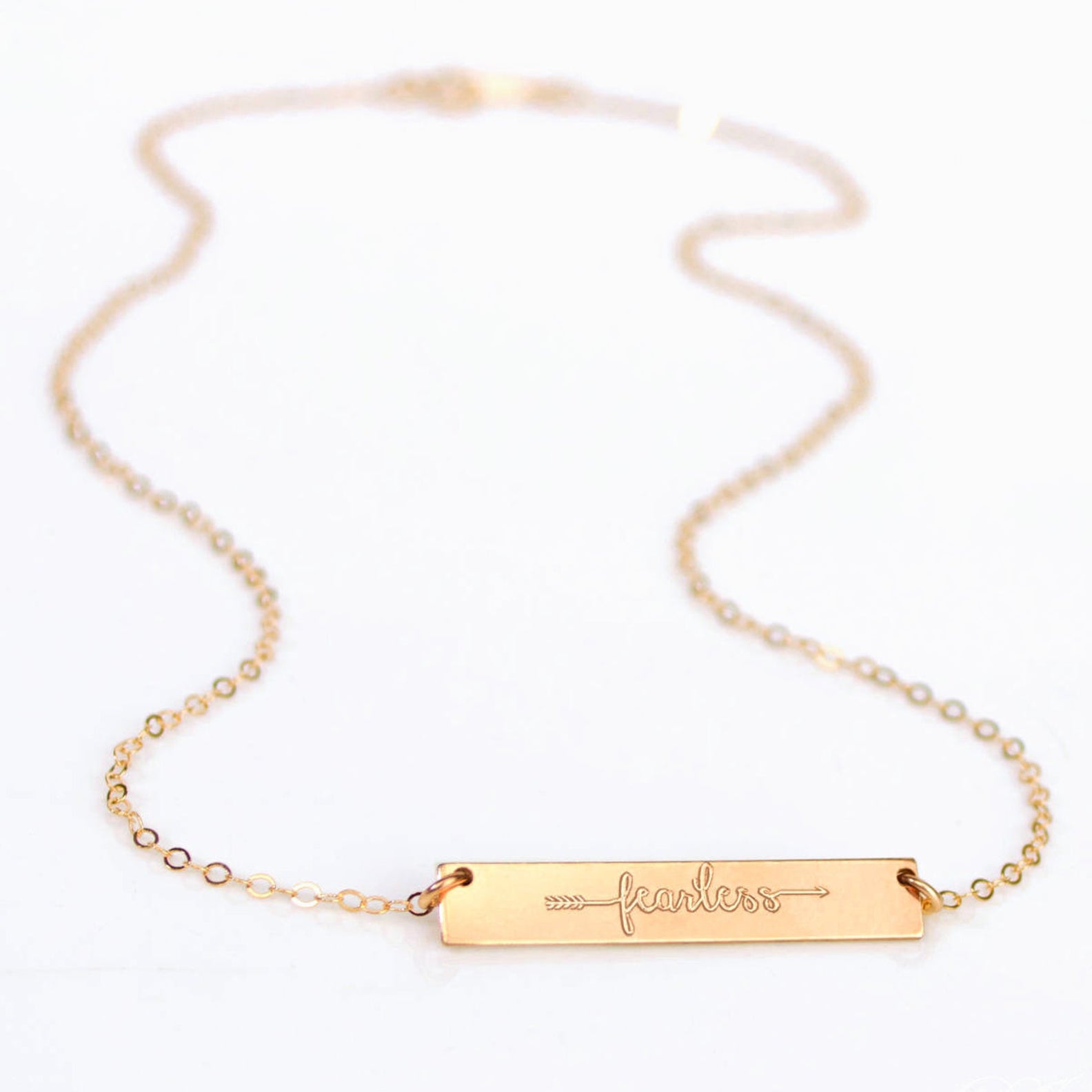Dainty gold bar necklace engraved with “fearless” and an arrow, minimalist inspirational jewelry in 14K gold filled, perfect gift for women, teens, graduates, and friends. Personalized motivational necklace for everyday wear.