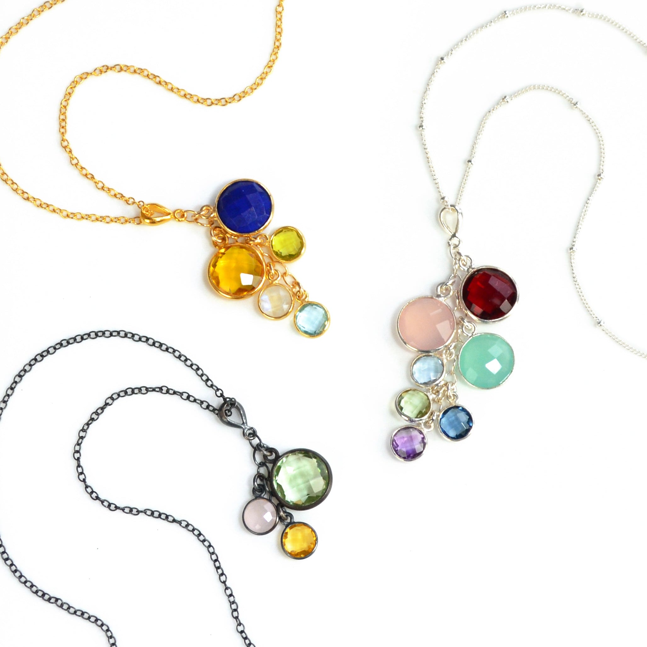 Set of three grandmother's necklaces one in gold with lapis, citrine, peridot, moonstone and blue topaz. Middle necklace is sterling silver with a satellite chain with garnet, pink chalcedony, aqua chalcedony, blue topaz, green amethyst, kyanite and purple amethyst. Oxidized silver necklace features green amethyst, pink chalcedony and citrine stones. 