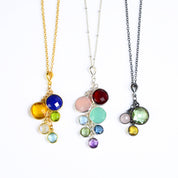 Set of three grandmother's necklaces one in gold with lapis, citrine, peridot, moonstone and blue topaz. Middle necklace is sterling silver with a satellite chain with garnet, pink chalcedony, aqua chalcedony, blue topaz, green amethyst, kyanite and purple amethyst. Oxidized silver necklace features green amethyst, pink chalcedony and citrine stones. 