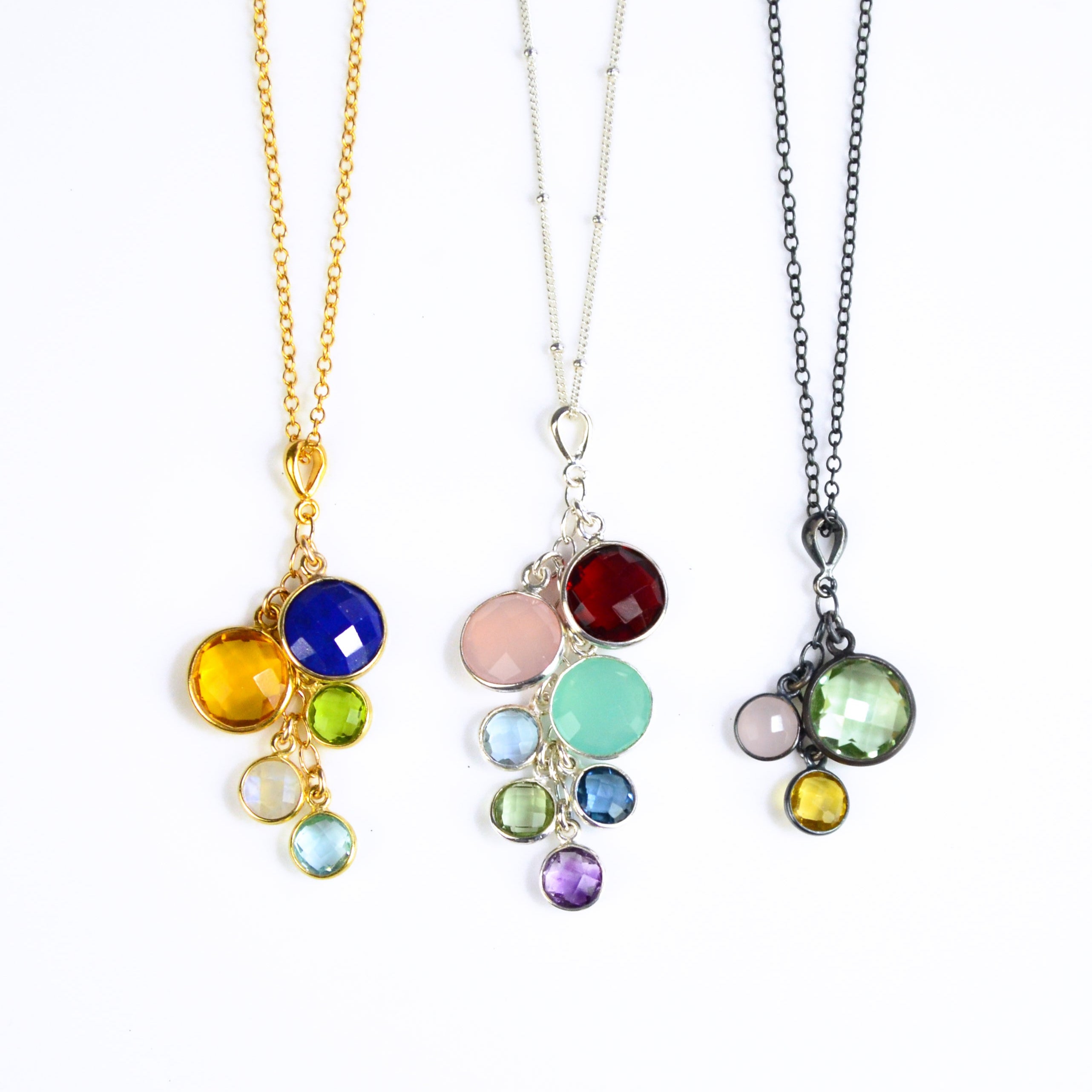 Set of three grandmother's necklaces one in gold with lapis, citrine, peridot, moonstone and blue topaz. Middle necklace is sterling silver with a satellite chain with garnet, pink chalcedony, aqua chalcedony, blue topaz, green amethyst, kyanite and purple amethyst. Oxidized silver necklace features green amethyst, pink chalcedony and citrine stones. 