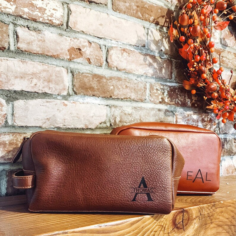 Engraved men's toiletry bag, personalized dopp kit, custom men's Rustic men’s leather toiletry bags engraved with initials, photographed against wood and seasonal décor. Perfect Christmas gift idea for men, husbands, or groomsmen.