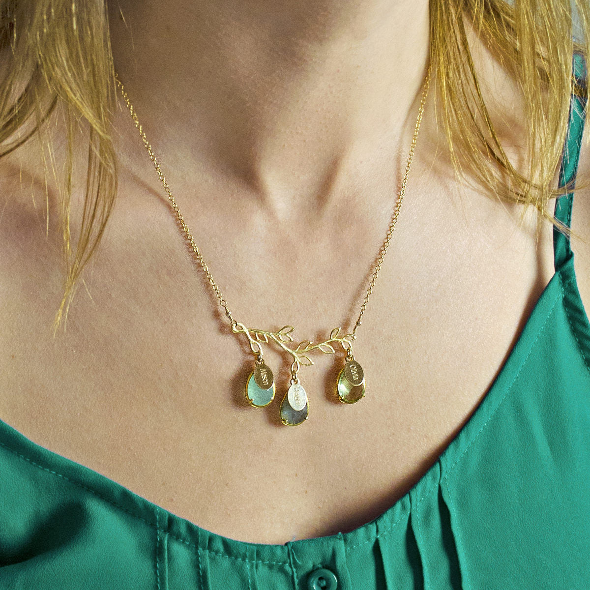 Woman wearing a personalized family tree necklace with colorful teardrop birthstones and engraved name tags.