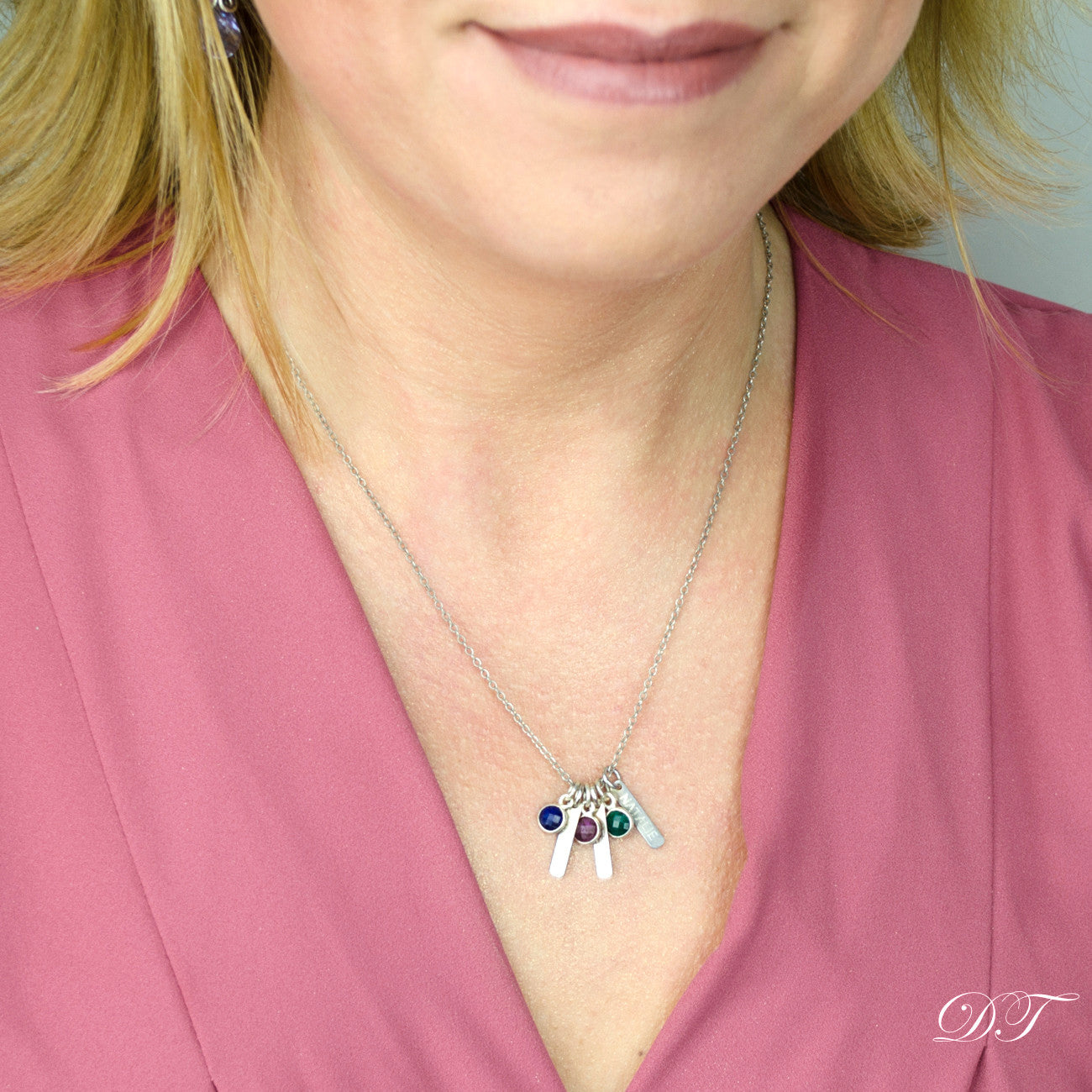 Model in pink top is wearing a sterling silver cable chain with three tiny name bars and gemstones including kyanite, purple amethyst, green onyx birthstones. 