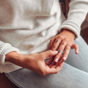 Model wearing three rings. One silver on the index finger with the ruby gemstone, two sterling silver rings on middle finger with garnet and green onyx stones. 