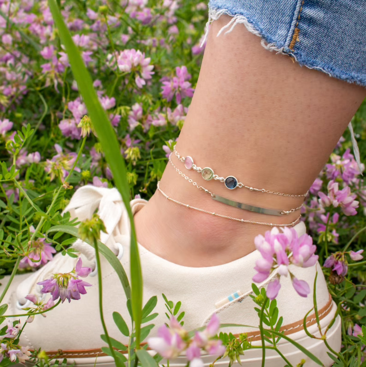 Model is stylishly layering our 6mm birthstone anklet with pink chalcedony, peridot and kyanite gemstones, a single sterling silver satellite chain and the skinny morse code bar necklace in sterling silver. 