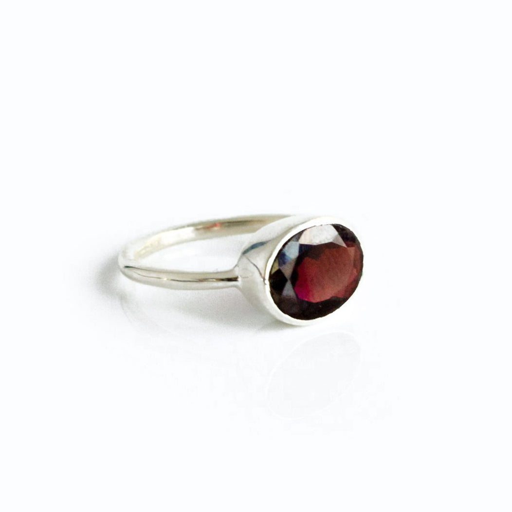 Sterling silver oval garnet ring, bezel setting with checker-faceted red gemstone; sleek minimalist January birthstone jewelry; durable 925 band for daily wear; stackable gemstone ring that pairs with gold vermeil and rose gold; meaningful birthday or graduation gift; handcrafted quality, nickel-free, comfortable fit.