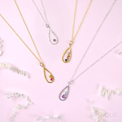 Two sterling silver teardrop pendant frame necklaces, one featuring a single garnet gemstone, one in our mother and child stone style with a 5mm purple amethyst and 3mm aqua chalcedony birthstones. Two gold filled open teardrop pendant necklaces one with peridot and ruby birthstones and one with blue topaz, purple amethyst and kyanite birthstones. 