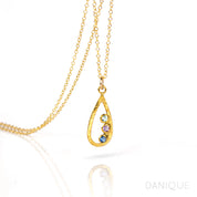 Single gold filled teardrop frame necklace with three 3mm birthstones including blue topaz, purple amethyst, and kyanite. 